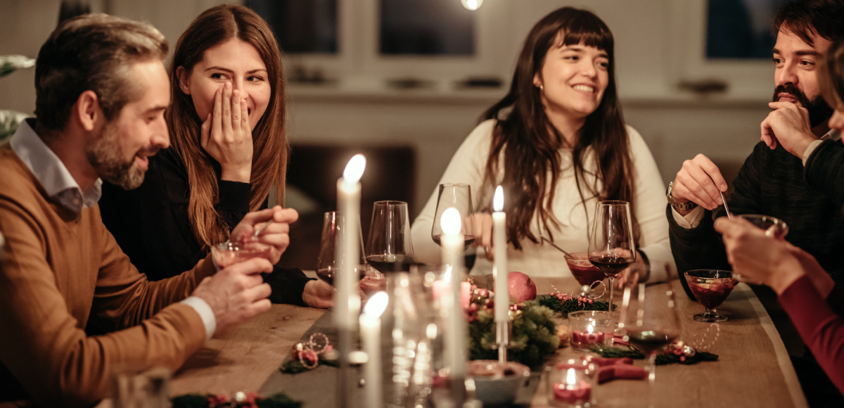 A group of friends gathered around a cheery dinner table, home for the holiday feast